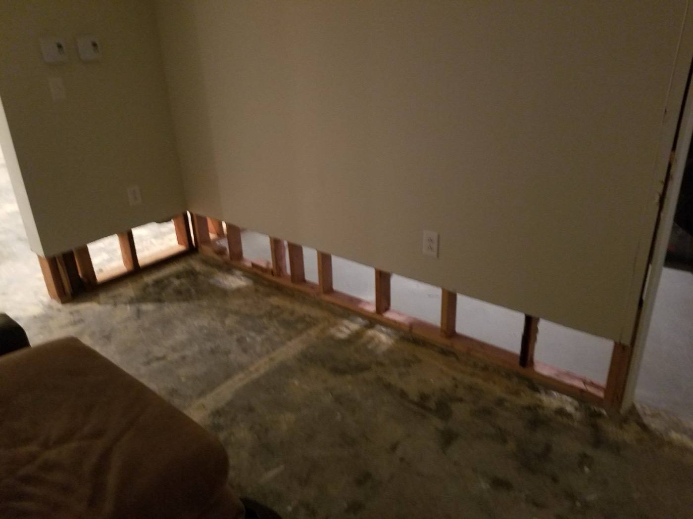 Basement corner with damaged drywall cut away and floor stripped