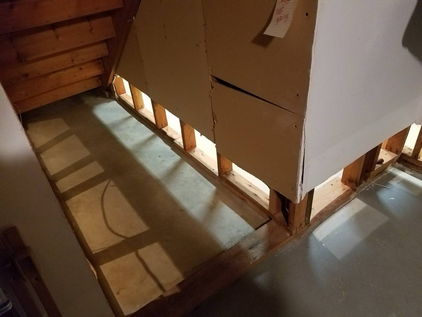 Drywall cut away under basement stairs during cleanup