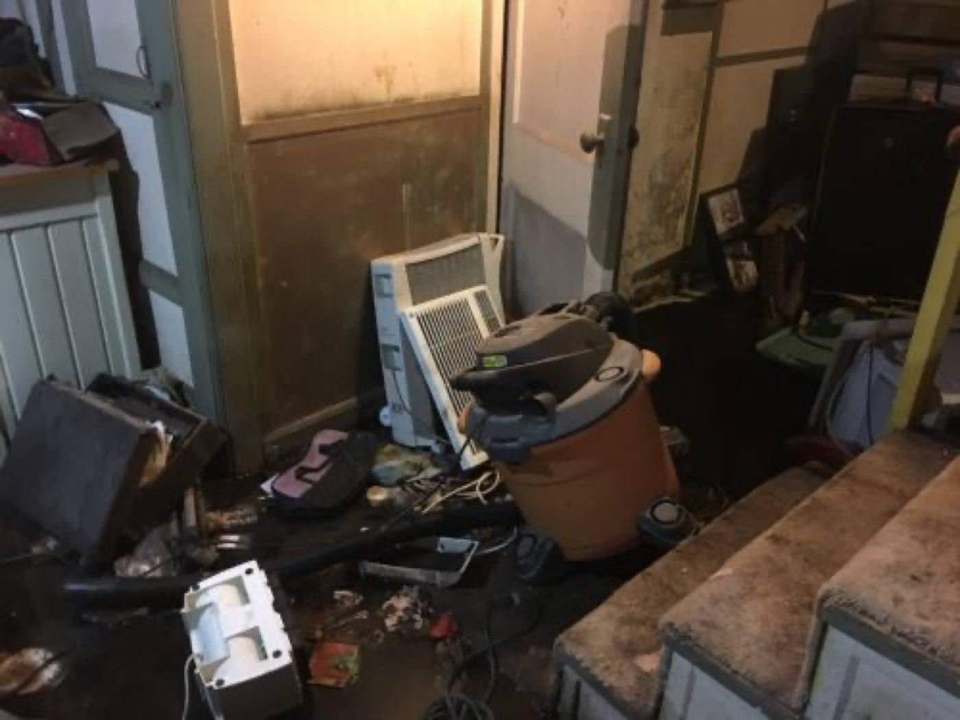 Water-damaged basement with debris and soaked stairs