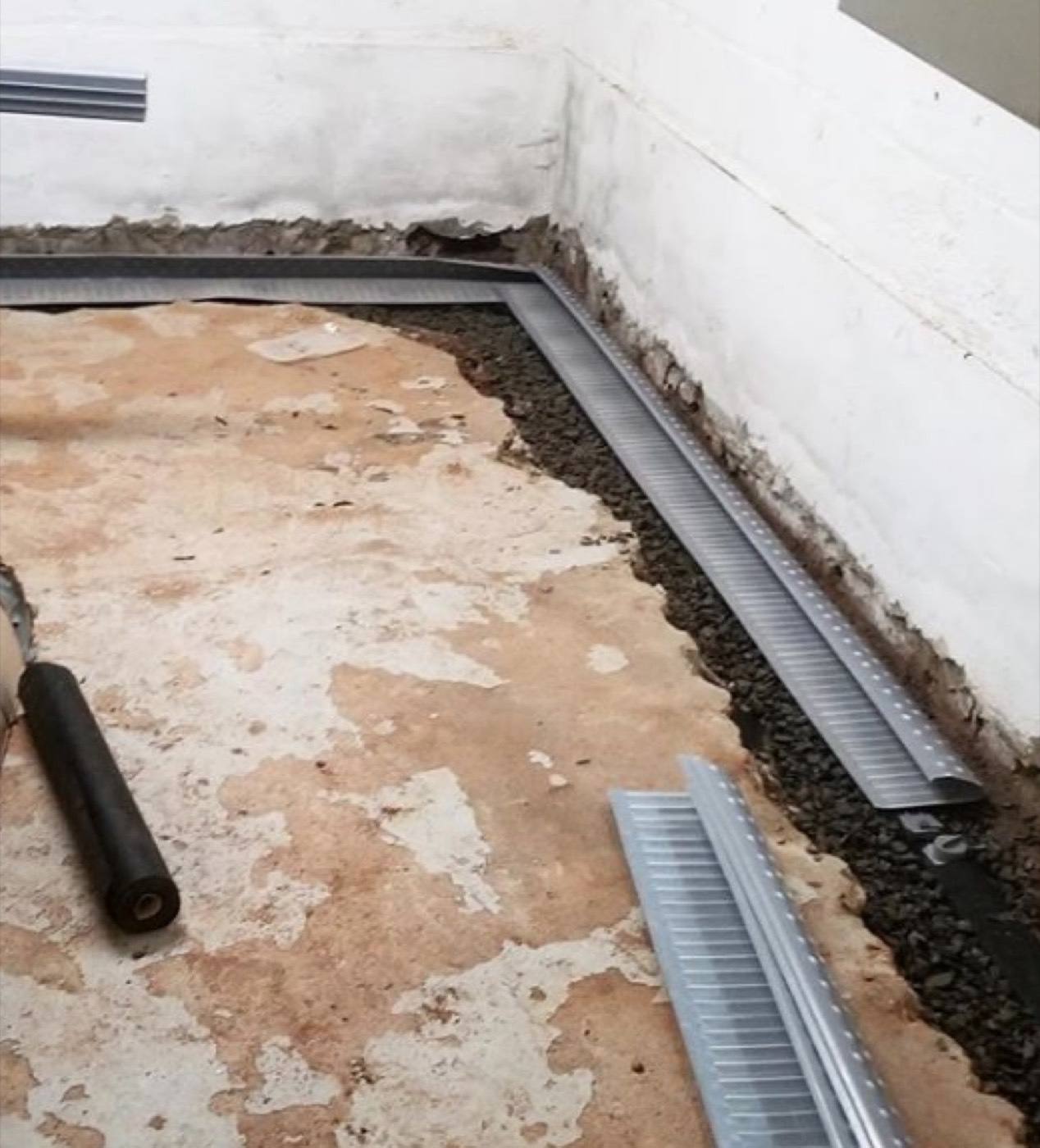 Interior French drain channel installed along the wall