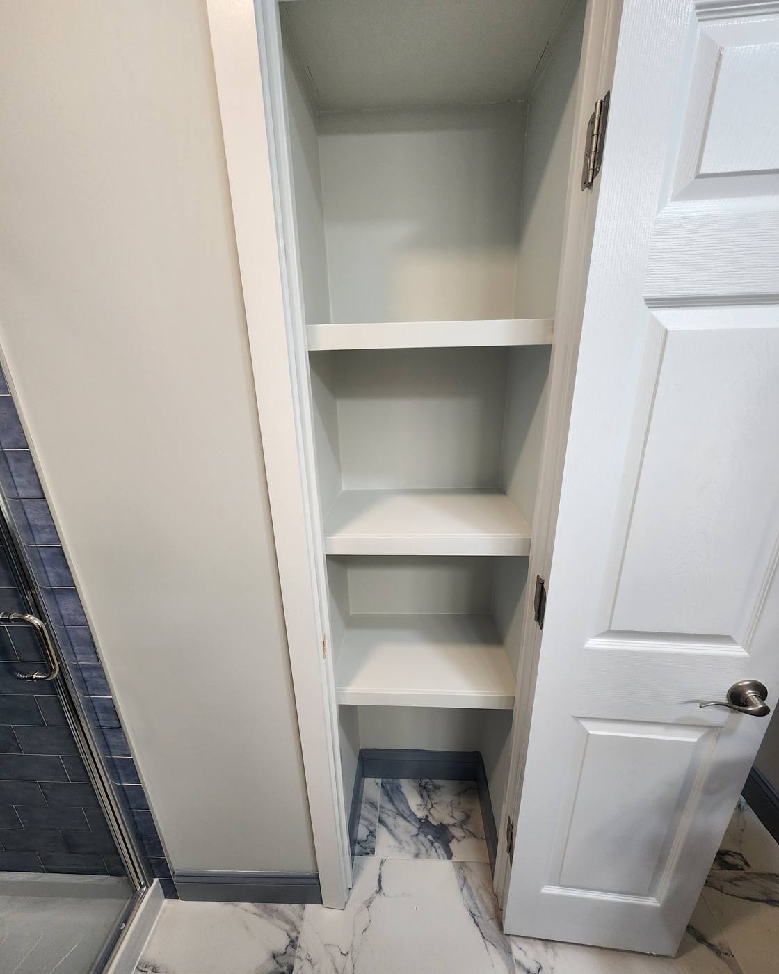 Built-in linen shelving beside a new tile shower