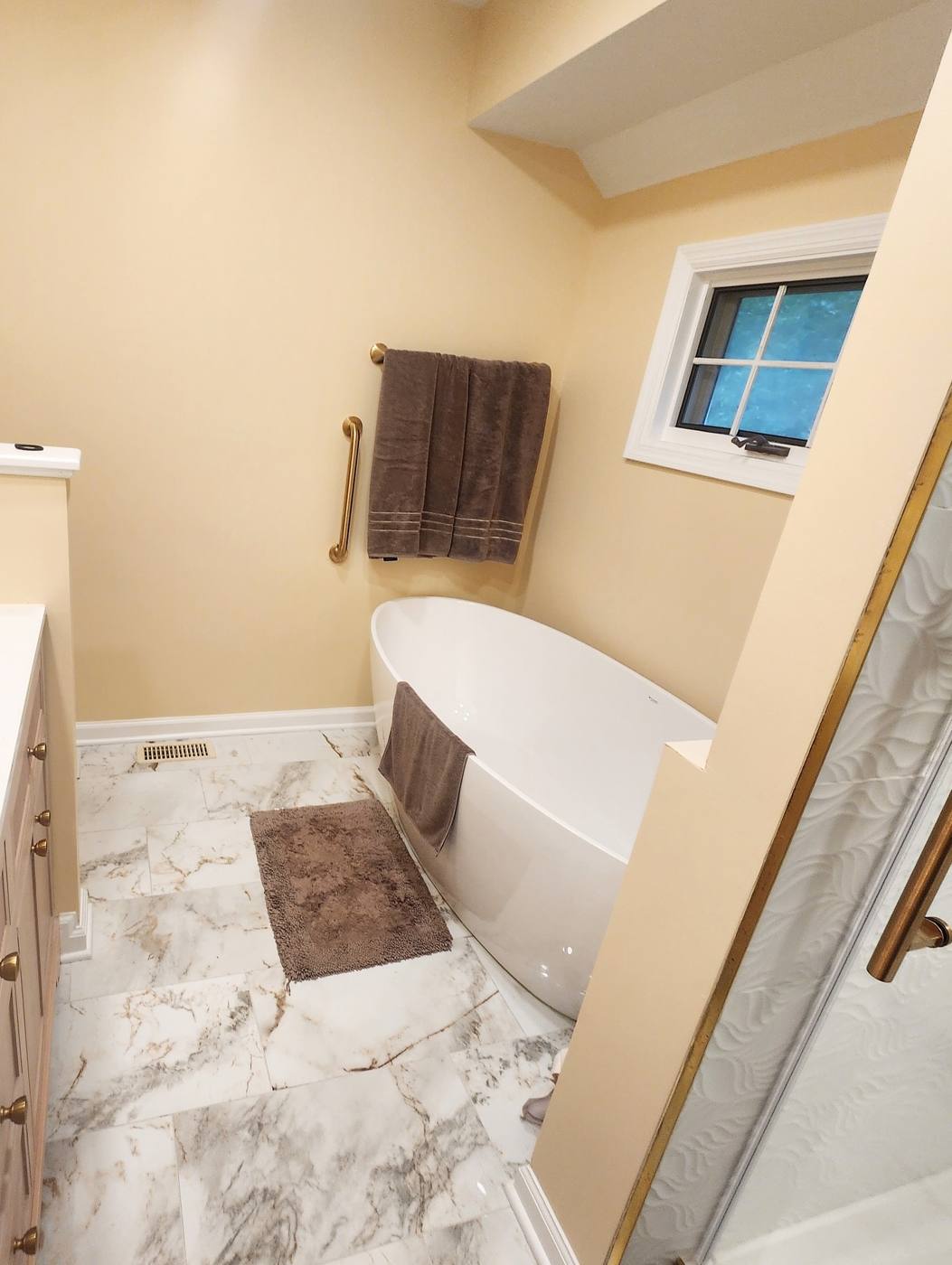 Freestanding soaking tub on marble-look porcelain tile