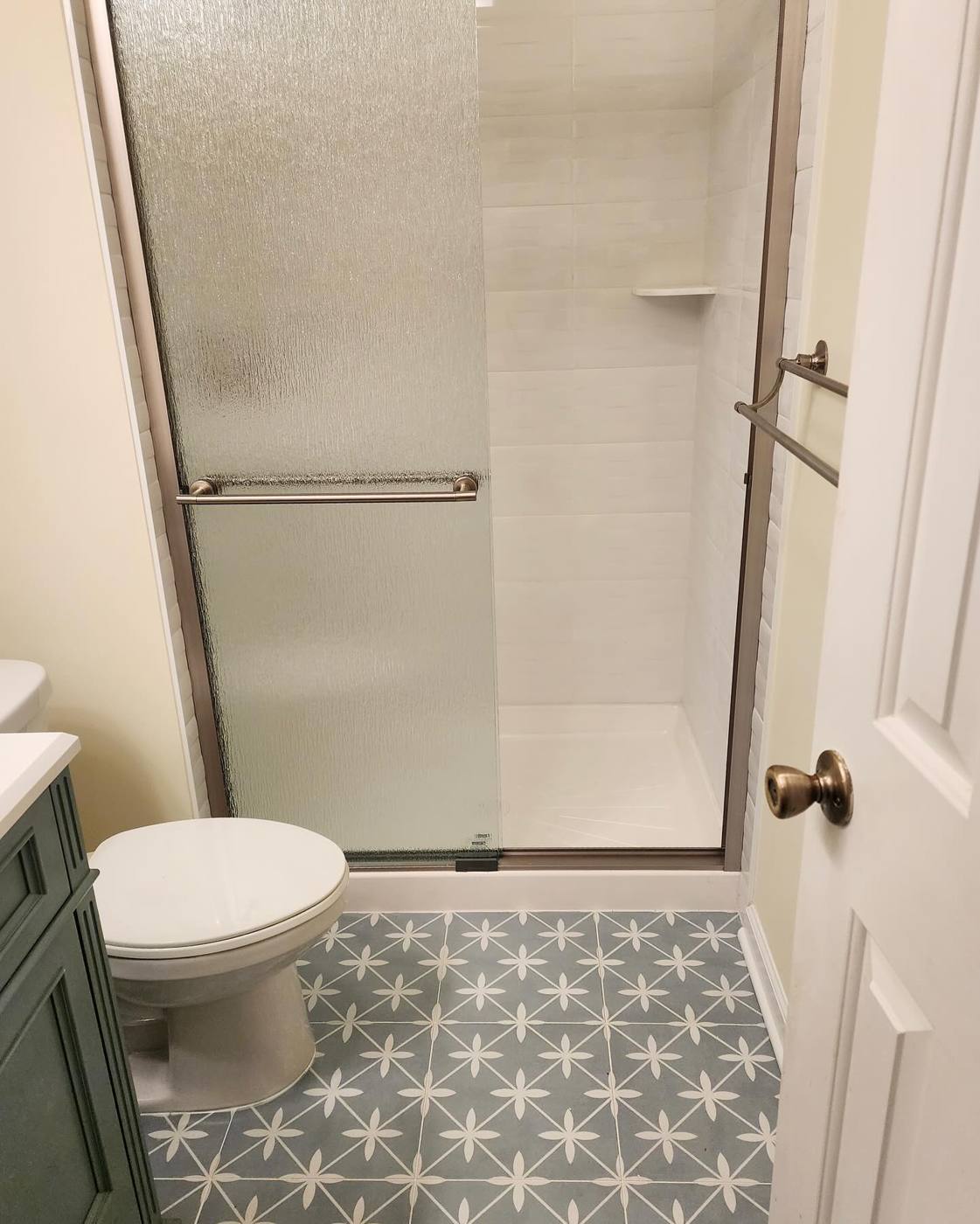 White shower with sliding glass door over star tile