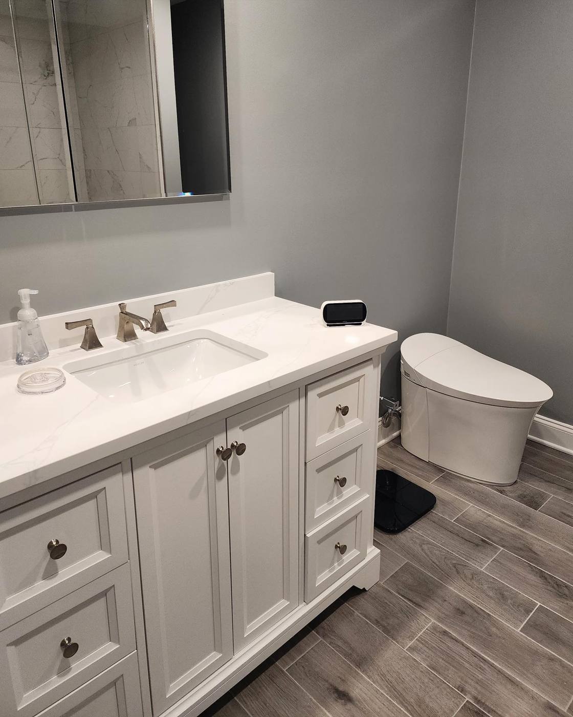 White shaker vanity with quartz top and a smart toilet