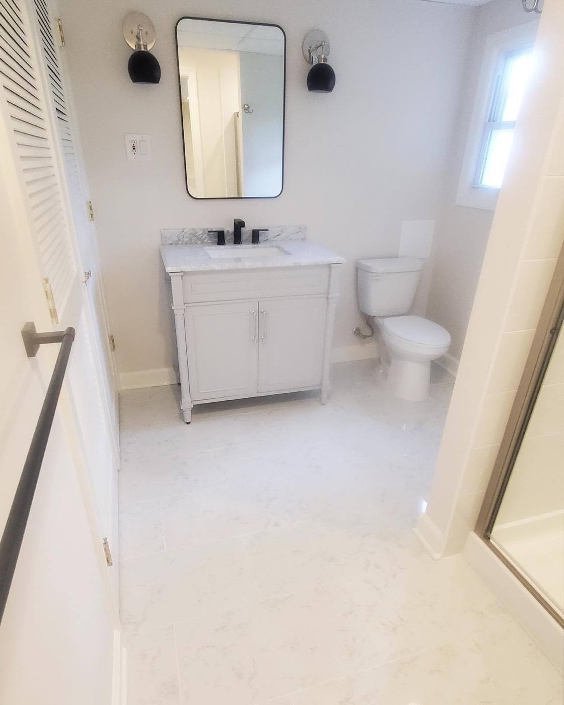 White vanity, black fixtures and marble-look floor